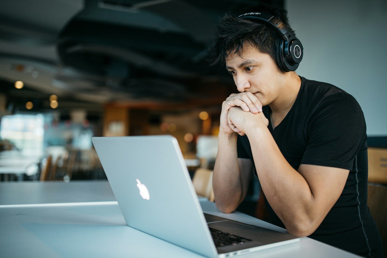 man wearing headphones while sitting on chair in front of MacBook